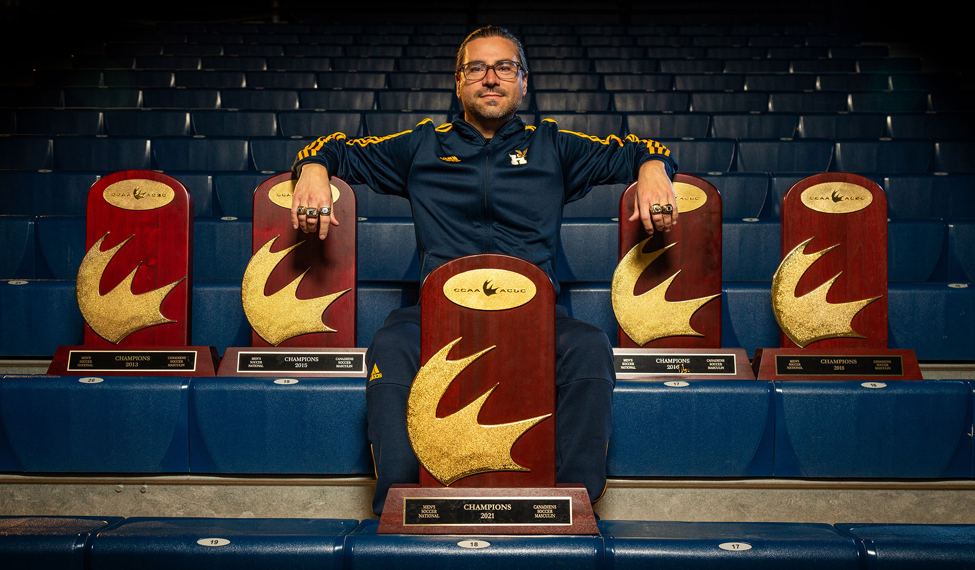 Coach Aquino posing with his five national championship trophies