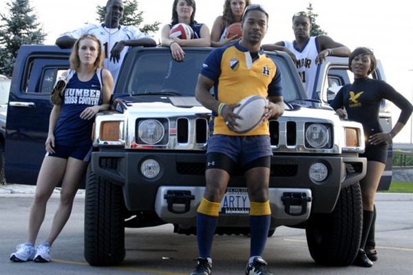 Dale posing in front of a Hummer with other Humber student-athletes