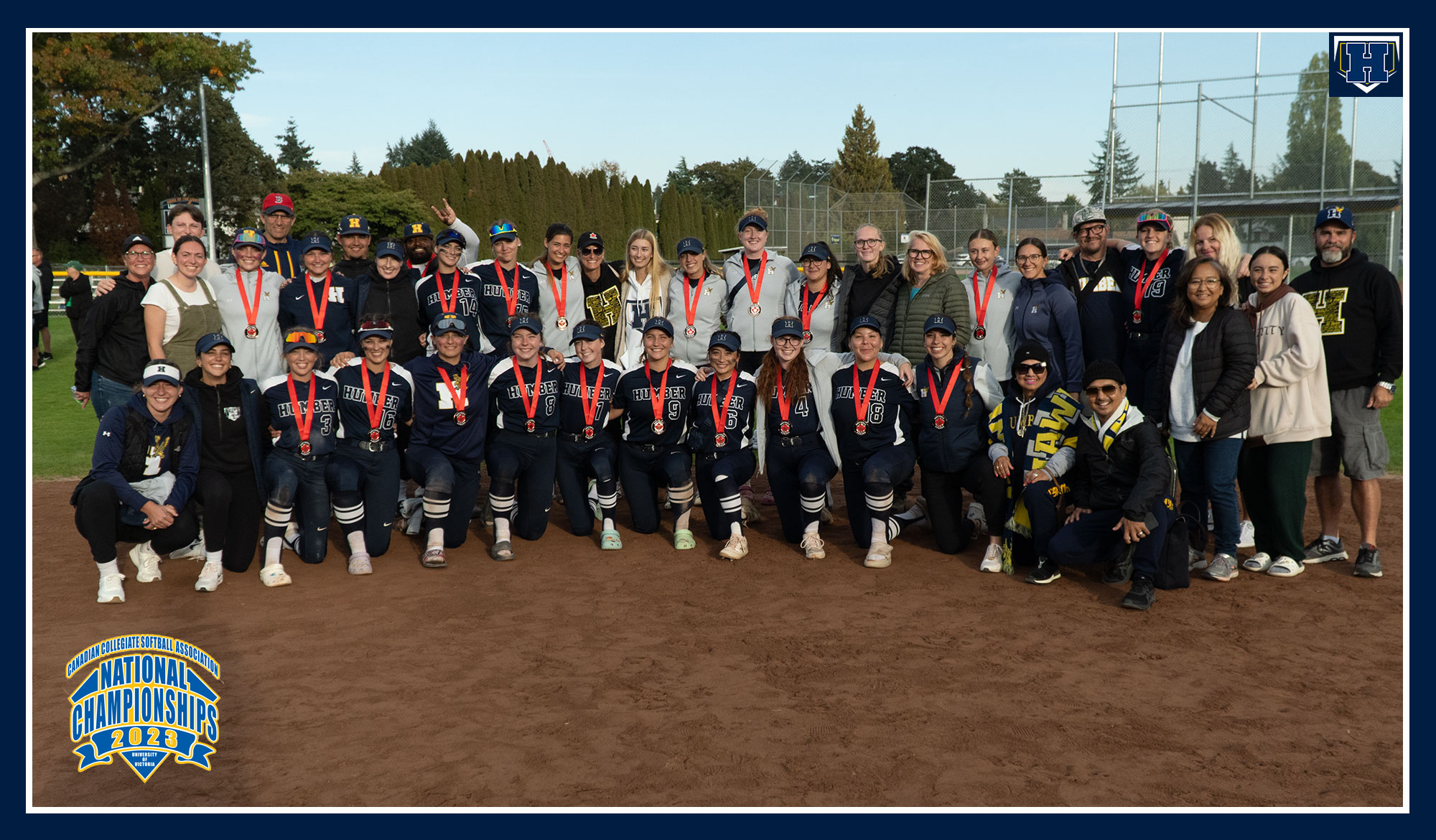 Softball team photo wearing their medals, surrounded by family and friends
